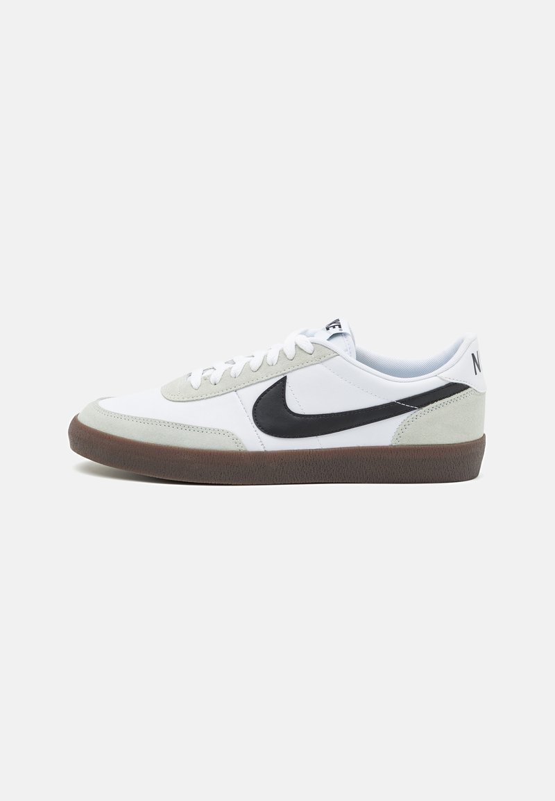 Trampki Nike z białą skórzaną cholewką, szarymi zamszowymi akcentami, czarnym logo Swoosh i brązową gumową podeszwą. Klasyczny design low-top.