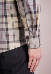 Langarm geruite overhemd met een mix van beige, grijs en zwart met rode accenten; zachte katoenstof, knoopmanchetten en een getailleerde pasvorm.