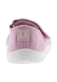 Scarpa di tela rosa con suola in gomma bianca e un occhiello in tessuto sul tallone, con un piccolo patch logo sul retro.