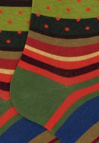 Calze a righe multicolori con strisce verdi, rosse, marroni e gialle con puntini rossi. Realizzate in tessuto morbido ed elastico.