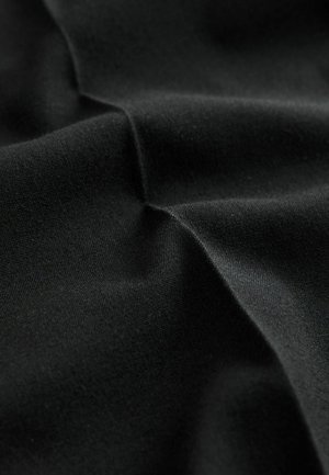 Sort stof med en glat tekstur, der har bløde folder og en mat finish. Materialet udviser let stræk og minimal lysrefleksion.