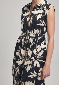 Floral jumpsuit in navy and cream, featuring a collared neckline, front zipper, elastic waist, and sleeveless design with a loose fit.