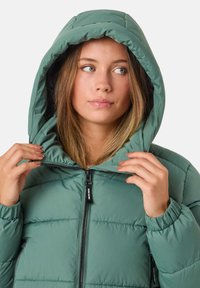 Zielona kurtka puchowa z kapturem, z pikowanym wzorem, przednim zamkiem błyskawicznym i elastycznymi mankietami. Gładka faktura i średnia grubość.