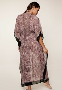 Kimono trasparente in stampa leopardata con sfumature di rosa e nero. Presenta maniche ampie, collo legato e un design fluido con aperture laterali.