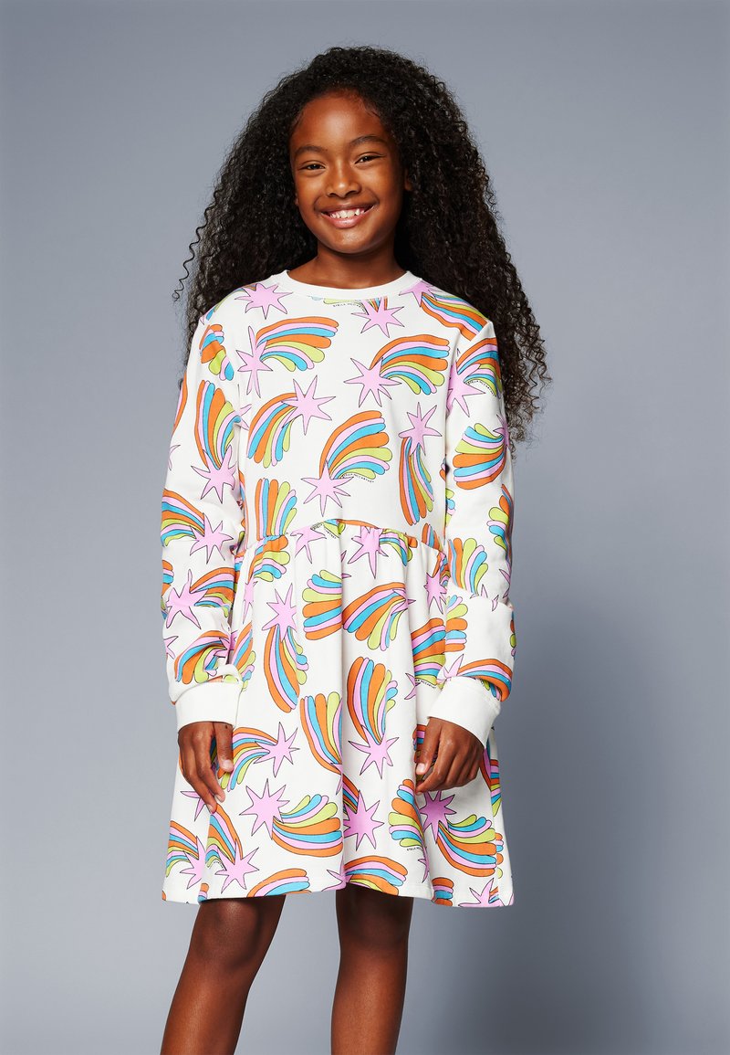 Φόρεμα με μακριά μανίκια σε λευκό ύφασμα που διαθέτει πολύχρωμο μοτίβο με ουράνιο τόξο και αστέρια. Η φούστα έχει φαρδιά σχεδίαση, με ριπτές μανσέτες.