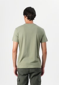 Olive green cotton t-shirt with short sleeves, crew neckline, and a straight hem. Smooth texture with minimal seams and no visible prints.