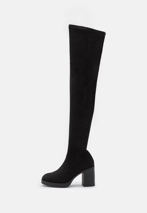 Bottes noires hautes jusqu'au-dessus du genou en daim, dotées d'un talon épais et d'une texture lisse, avec un design élégant sans motifs visibles.