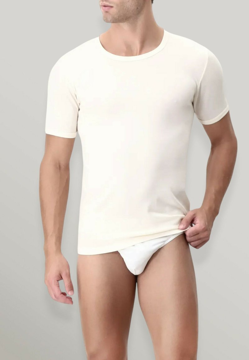 T-shirt beige a maniche corte realizzato in tessuto morbido con collo rotondo. La maglietta aderisce bene al torace e presenta un bordo a contrasto.