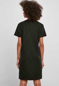Black cotton t-shirt dress with a loose fit, short sleeves, and a crew neckline, ending just above the knees, smooth texture, simple design.