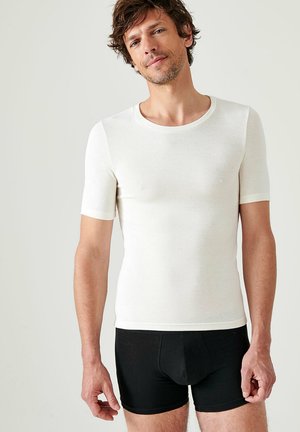 Short-sleeve, fitted white t-shirt made of soft fabric, paired with black boxer briefs. The shirt features a rounded neckline and smooth texture.