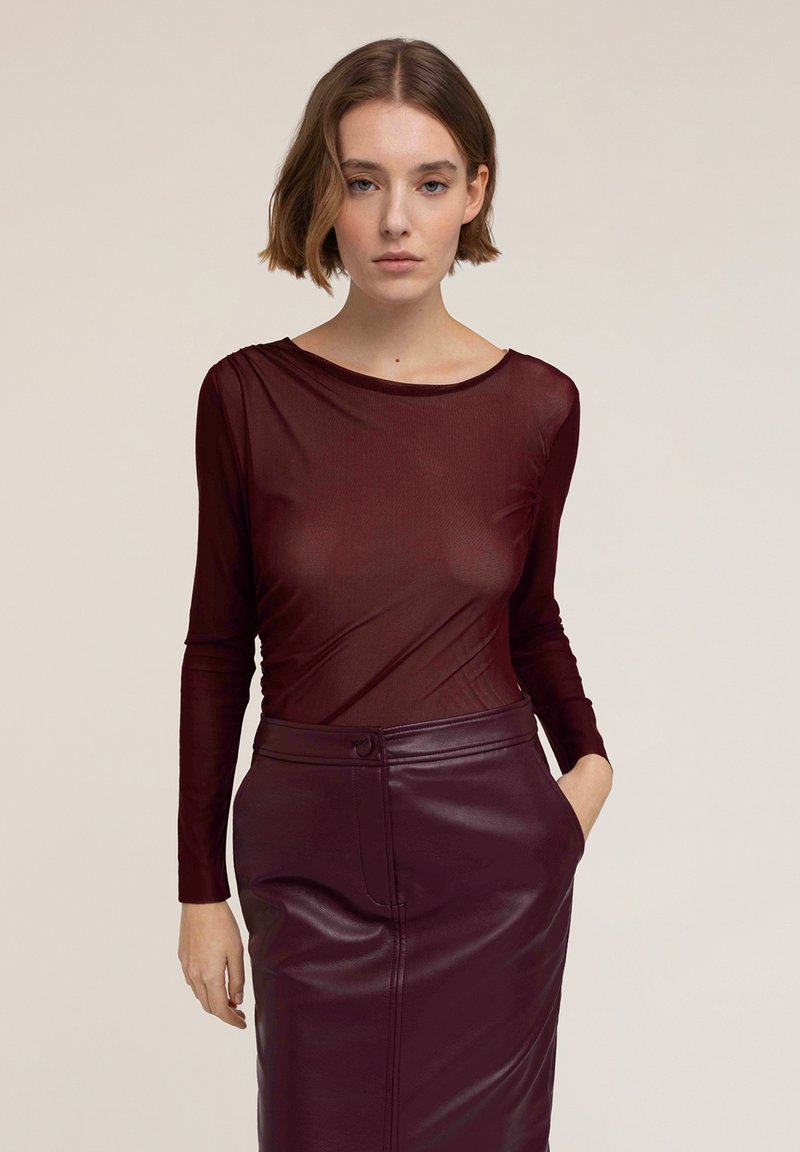 Bordeaux lange mouw top van doorschijnend materiaal, gecombineerd met een bijpassende high-waisted leren rok, met een gladde textuur en een getailleerd ontwerp.
