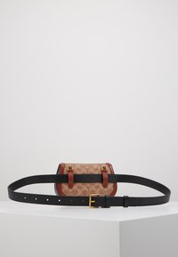 Belt taske med en tan mønstret krop, brune læderdetaljer og en sort justerbar rem. Har guldtonet hardware og dobbelt side løkker.