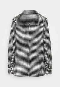 Sort-hvid ternet jakke med krave, knapdetaljer på ærmerne og lige snit. Tekstureret stof med klassisk mønster.