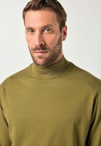 Suéter de cuello alto verde oliva hecho de una tela suave, con un diseño ajustado y cuello acanalado para detalles texturizados.
