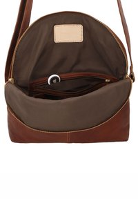 Bruine leren crossbodytas met open ritssluiting die een klein wit volgapparaat toont in een binnenzak met rits.