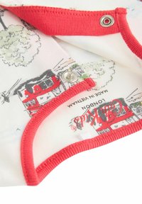 Weißer Stoff mit rotem Saum, der ein gedrucktes Design von Londoner Wahrzeichen zeigt. Nahaufnahme zeigt einen Druckknopf und eine weiche Textur.