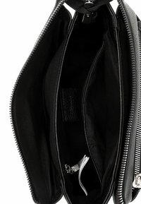 Czarna skórzana torebka z detalami z srebrnym zamkiem błyskawicznym. Posiada wiele przegródek, wewnętrzną podszewkę z tkaniny oraz małą kieszonkę na zamek wewnątrz.