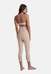 Body nude senza cuciture con design senza spalline, lunghezza fino al polpaccio, superficie liscia e senza cuciture visibili. Presenta una chiusura con una larga tracolla sul retro.