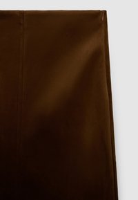 Brauner Wildlederstoff mit glatter Textur, ausgestattet mit einem seitlichen Reißverschluss und einem gerade geschnittenen Design, betont einen monochromen Look.