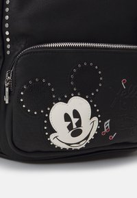 Schwarzer Kunstleder-Rucksack mit Mickey-Maus-Design, metallischen Nieten, einer Reißverschlusstasche und musikalischen Notenakzenten.