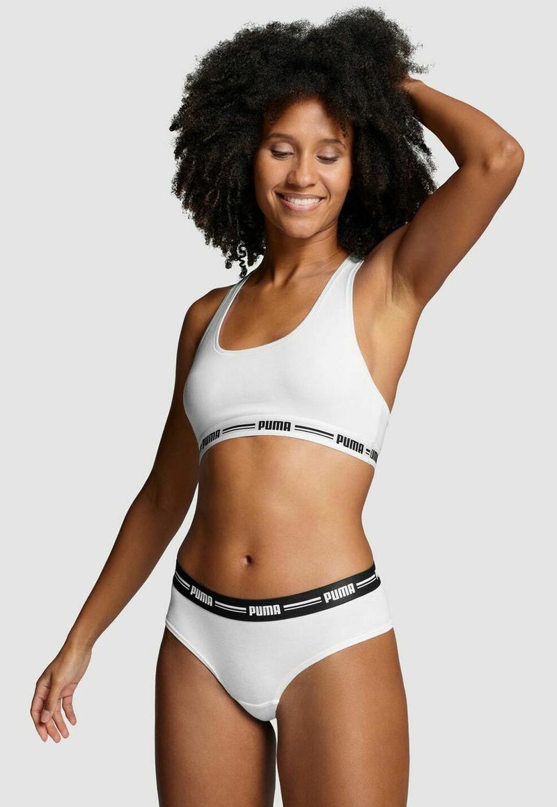 White sports bra and matching underwear with black elastic bands displaying the "PUMA" logo. Smooth fabric with a fitted design.