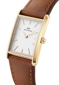 Reloj rectangular dorado con esfera blanca, correa de cuero marrón, marcadores de hora minimalistas y detalle en la corona. Costuras visibles en la correa.