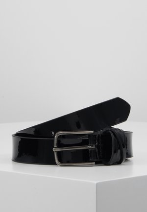 Glossy black leather belt coiled on a white surface with a silver rectangular buckle and pointed end visible.
