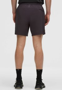 Miestne tmavošedé športové šortky, vyrobené z ľahkého materiálu s hladkou textúrou a elastickým pásom. Majú jemné branding.