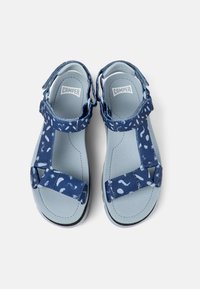Blå sandaler med texturerade remmar som har ett mönster av vita former, justerbar spänne, vadderad fotbädd och en robust gummisul.