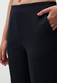 Marineblauwe broek van gemêleerde stof, met een recht uiterlijk, een elastische tailleband en zijzakken voor functionaliteit.