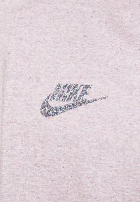 Světle šedá mikina s třpytivým multikolorovým logem Nike na levé straně. Jemná textura s decentními tečkami po celé látce.