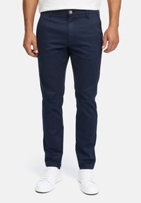 Marineblå bomuldsbukser med slim fit, der har en enkelt knaplukning, sidelommer og en glat tekstur. Sammen med hvide sneakers.