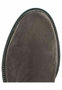 Botte en daim gris avec un bout arrondi, une surface texturée, et une semelle en caoutchouc noire avec un bord nervuré.