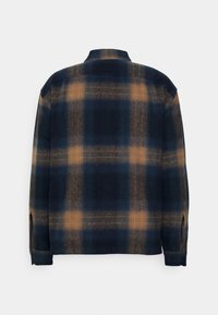 Marineblauw en oranje geruite shirt, flanelmateriaal, lange mouwen, knoopmanchetten, standaard kraag, achterkant zichtbaar met patroon en structuur.