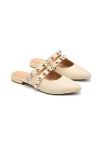 Chaussures beiges à enfiler avec bouts pointus, dotées de deux brides ornées d'accents circulaires métalliques et d'un talon plat. Texture lisse.