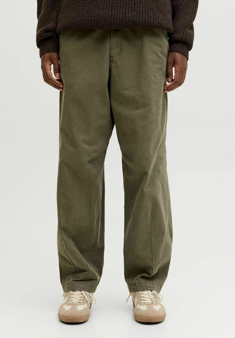 Pantaloni larghi color verde oliva realizzati in morbido cotone, con una vestibilità rilassata, tasche laterali e una finitura leggermente testurizzata, abbinati a sneakers beige.