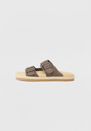 Brun ruskind slide sandal med to justerbare spænder og en beige polstret sål på hvid baggrund.