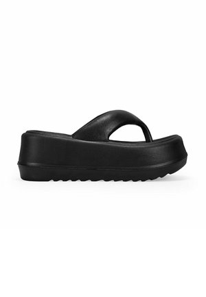 Sandalias de plataforma negras hechas de material suave, con una cinta superior ancha y una suela gruesa y texturizada con un patrón en forma de ola.