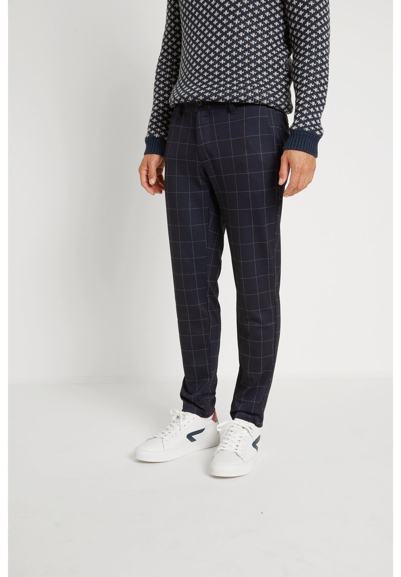 Námořnické kostkované kalhoty s tailoring fit, s hladkou texturou a jemným čtvercovým vzorem, doplněné bílými teniskami.