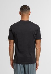 Černé tričko s krátkým rukávem a kulatým výstřihem, vyrobené z bavlny, pravidelného střihu, hladké textury, bez viditelných vzorů nebo kovových částí.