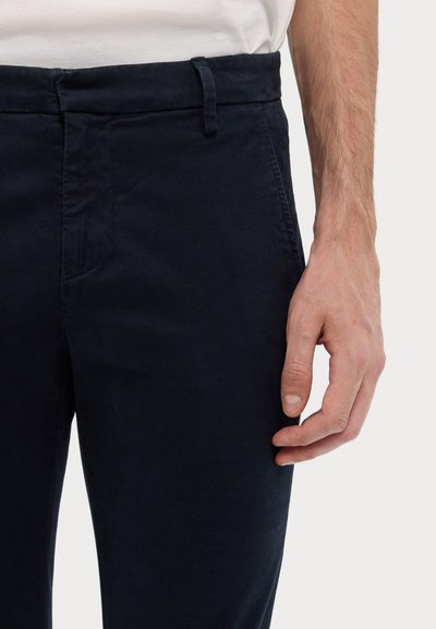 Mørkeblå chinos laget av glatt bomullsstoff, med slank passform, sidelommer og flat foran med en ren midjebånd.