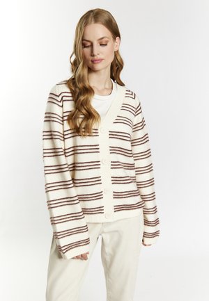 Cardigan crema con strisce orizzontali bordeaux, con bottoni frontali e polsini a costine. Indossato sopra una camicia bianca, presenta un design a scollo a V.