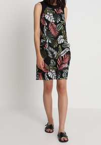 Black sleeveless dress with a leaf pattern in green, white, and pink. Rounded neckline, side pockets, and a straight cut finish.