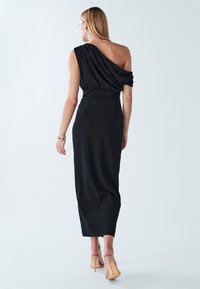 Must rindadega üksõlaline kleit, millel on ühel küljel drapeeritud kangas, kitsas lõige, põrandapikkune ja sileda tekstuuriga. Kandmiseks koos alasti toonis kontsakingadega.