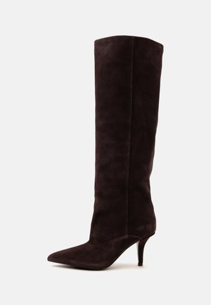 Bottes hautes jusqu'au genou en daim marron foncé avec bout pointu et talon fin de hauteur moyenne sur un fond clair.