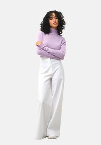 Maglione a collo alto lilla con maniche lunghe abbinato a pantaloni bianchi a vita alta e gamba larga; texture morbide e vestibilità comoda.