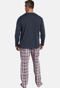 Men's loungewear set featuring a long-sleeve navy top and plaid pants with red, white, and blue tones, crafted from soft cotton fabric.