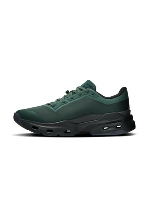 Scarpa da ginnastica sportiva verde scuro con suola nera, caratterizzata da fori di ventilazione, tomaia in tessuto a rete e chiusura con lacci, mostrata in profilo laterale.
