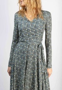 Langärmdresse met een blauw en crèmekleurig bloemmotief, een V-halslijn en een gestrikte taille met vloeiend materiaal.