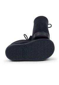 Botas de tobillo de ante negro con suelas de goma texturizadas y dos tiradores. Las suelas presentan un patrón ondulado y un texto grabado que indica el origen.